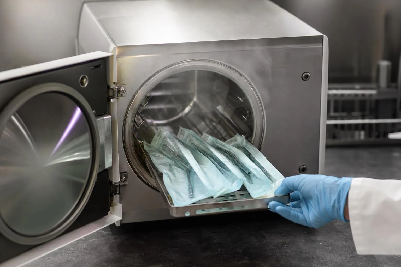 Porte ouverte d’un autoclave de paillasse dont les plateaux d’instruments emballés sont extraits en fin de cycle